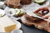 Frau streicht Butter auf ein Stück Vollkornbrot Frau streicht Butter auf ein Stück Vollkornbrot